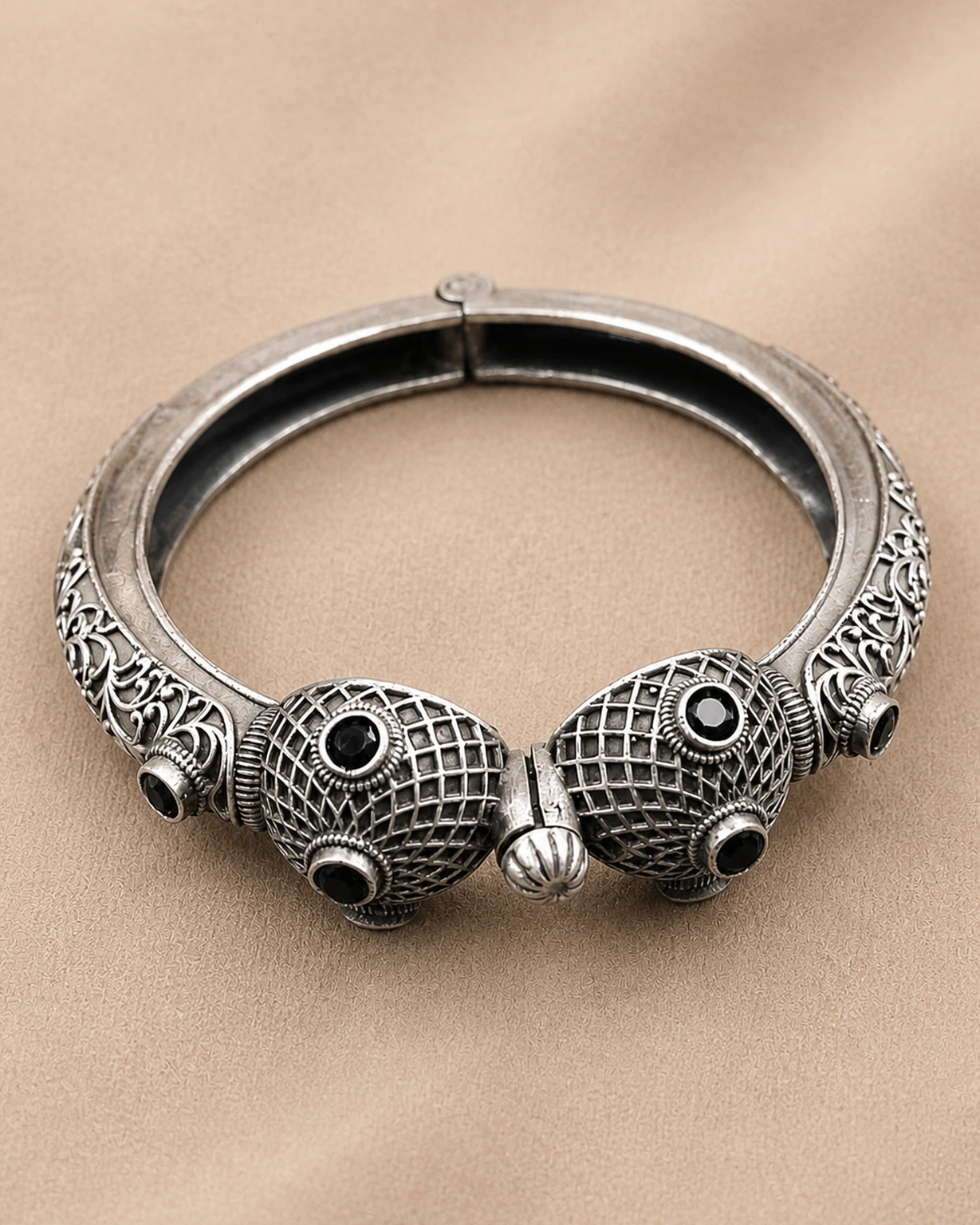Designer silver kada bracelet shown in a detailed close-up on pale beige.