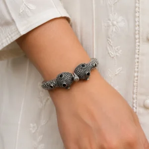 Designer silver kada bracelet worn naturally with an ivory outfit.