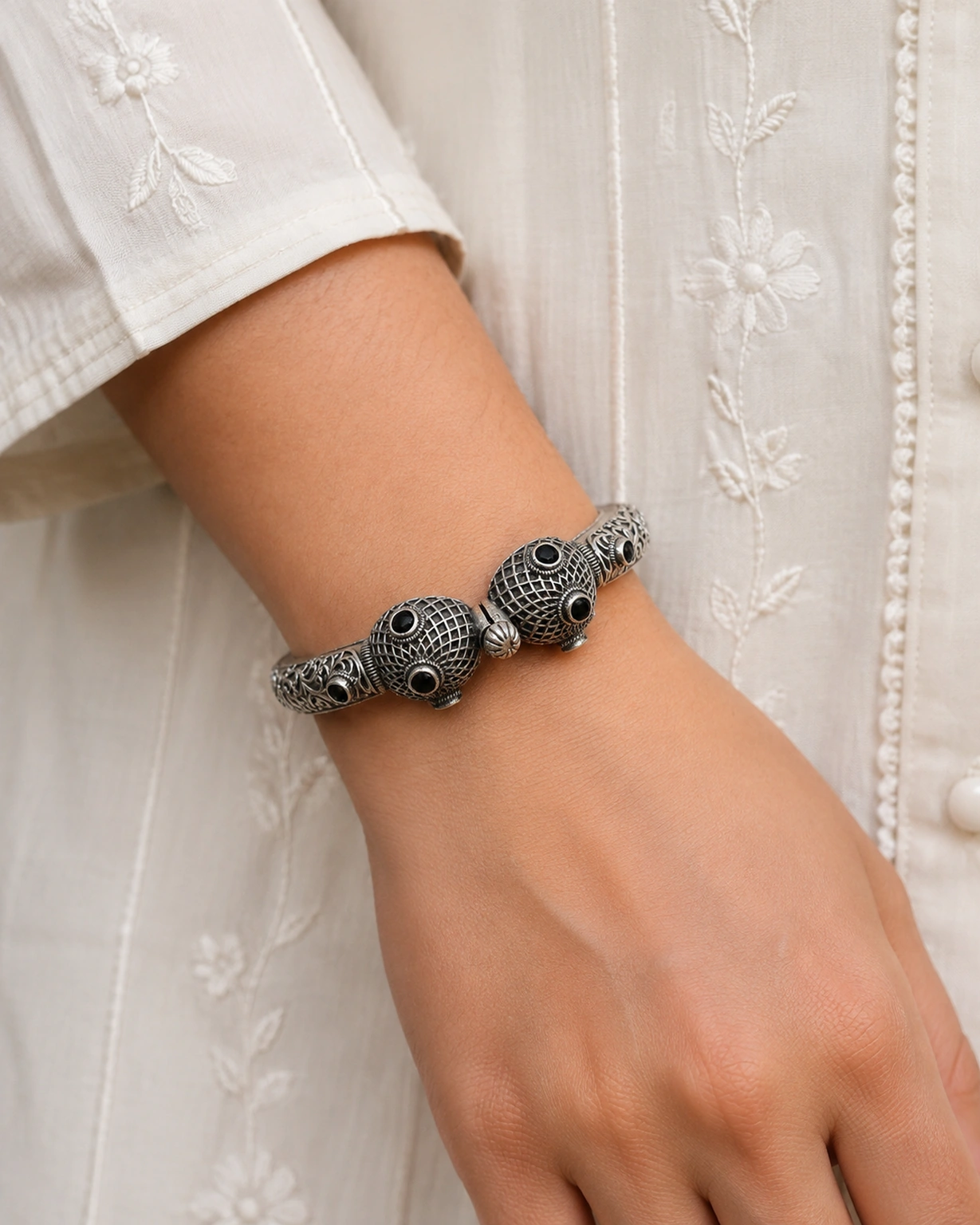 Designer silver kada bracelet worn naturally with an ivory outfit.