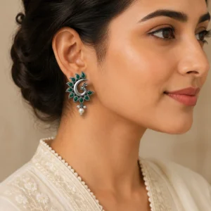 Elegant peacock earrings worn naturally with an ivory outfit.