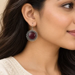 Maroon floral round hook earrings worn naturally with an ivory outfit.