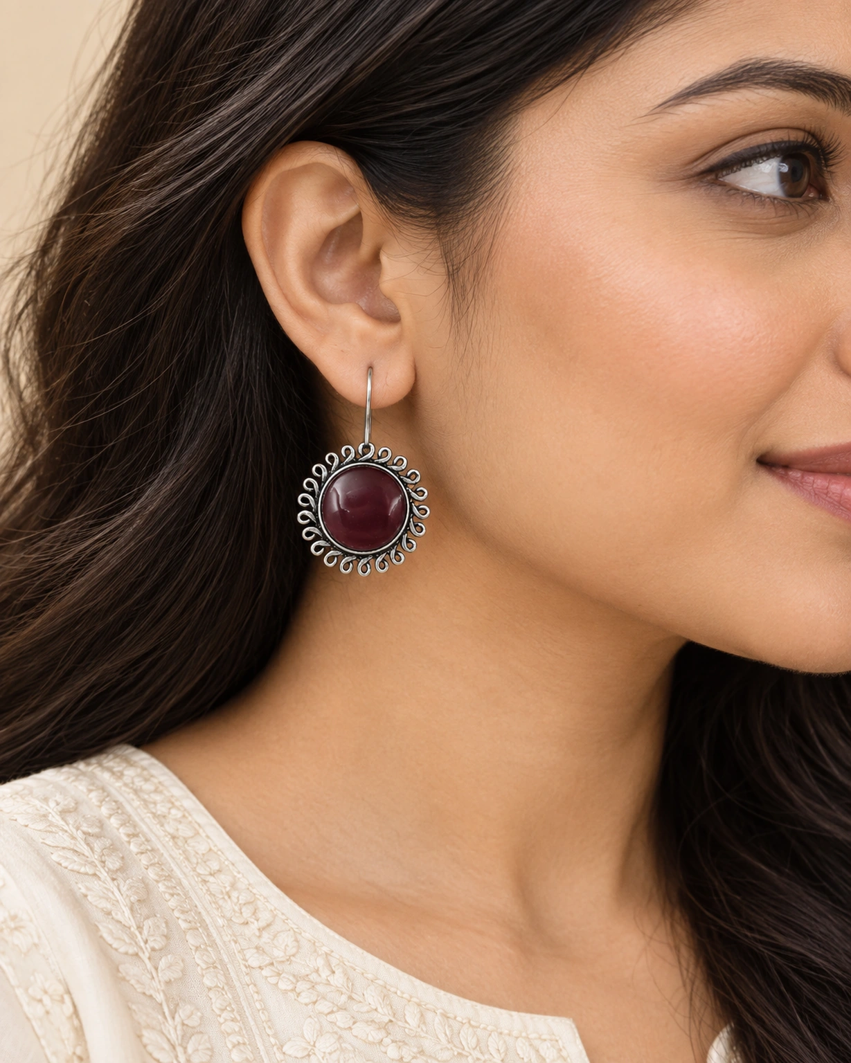 Maroon floral round hook earrings worn naturally with an ivory outfit.