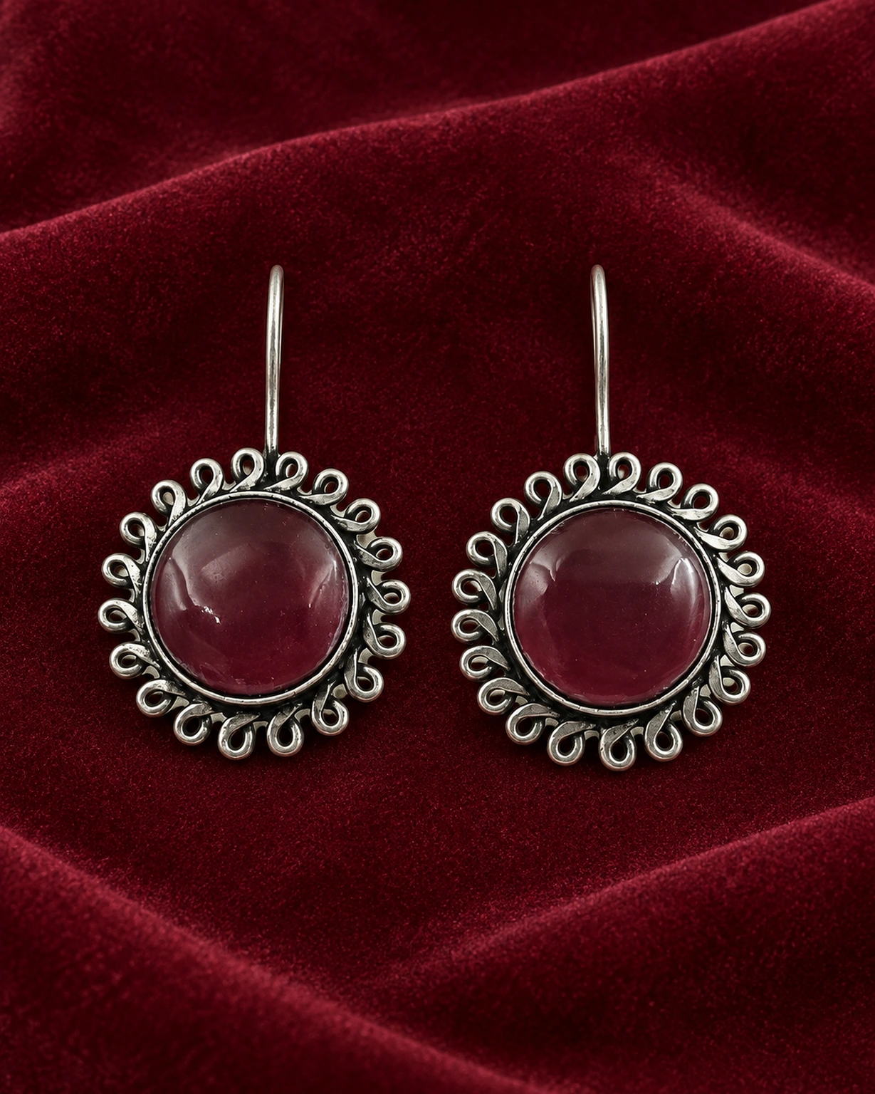 Maroon floral round hook earrings displayed on rich burgundy velvet.