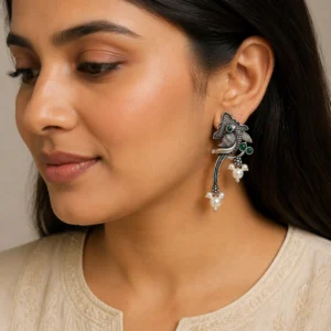 Green oxidized unique bird earrings worn naturally with an ivory outfit.
