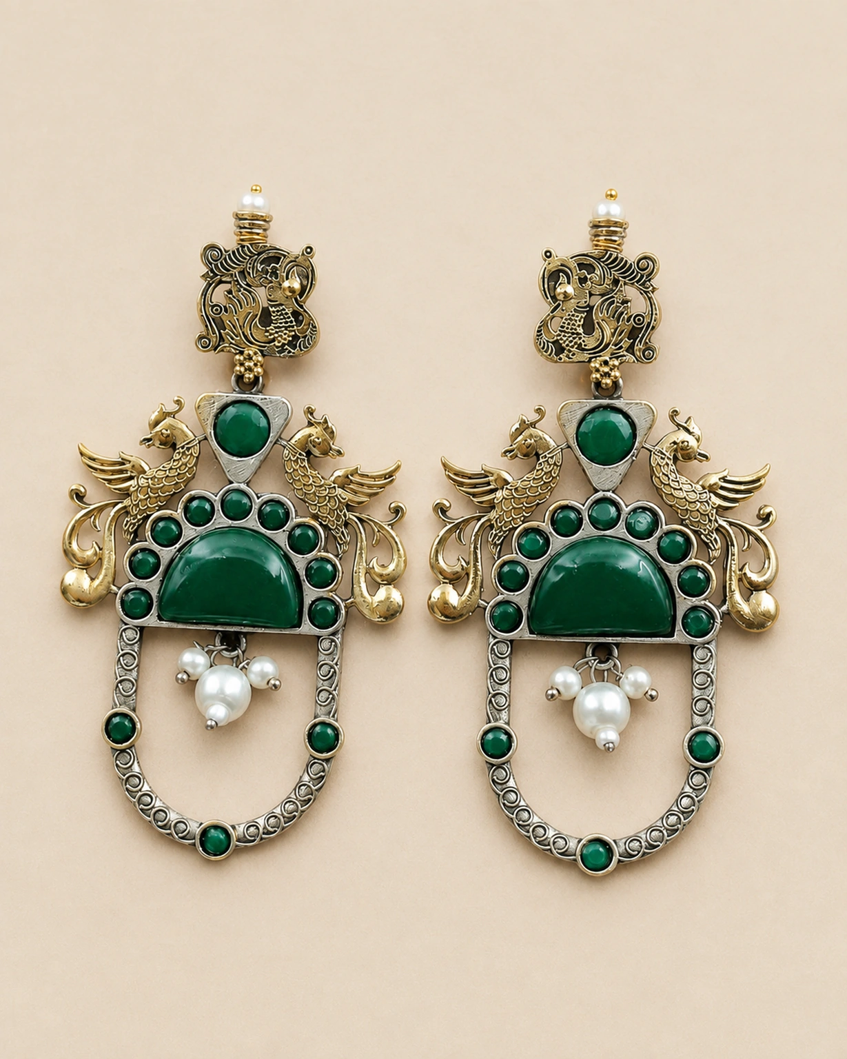Green two-tone peacock earrings shown in a detailed close-up on pale beige.
