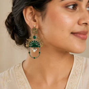 Green two-tone peacock earrings worn naturally with an ivory outfit.