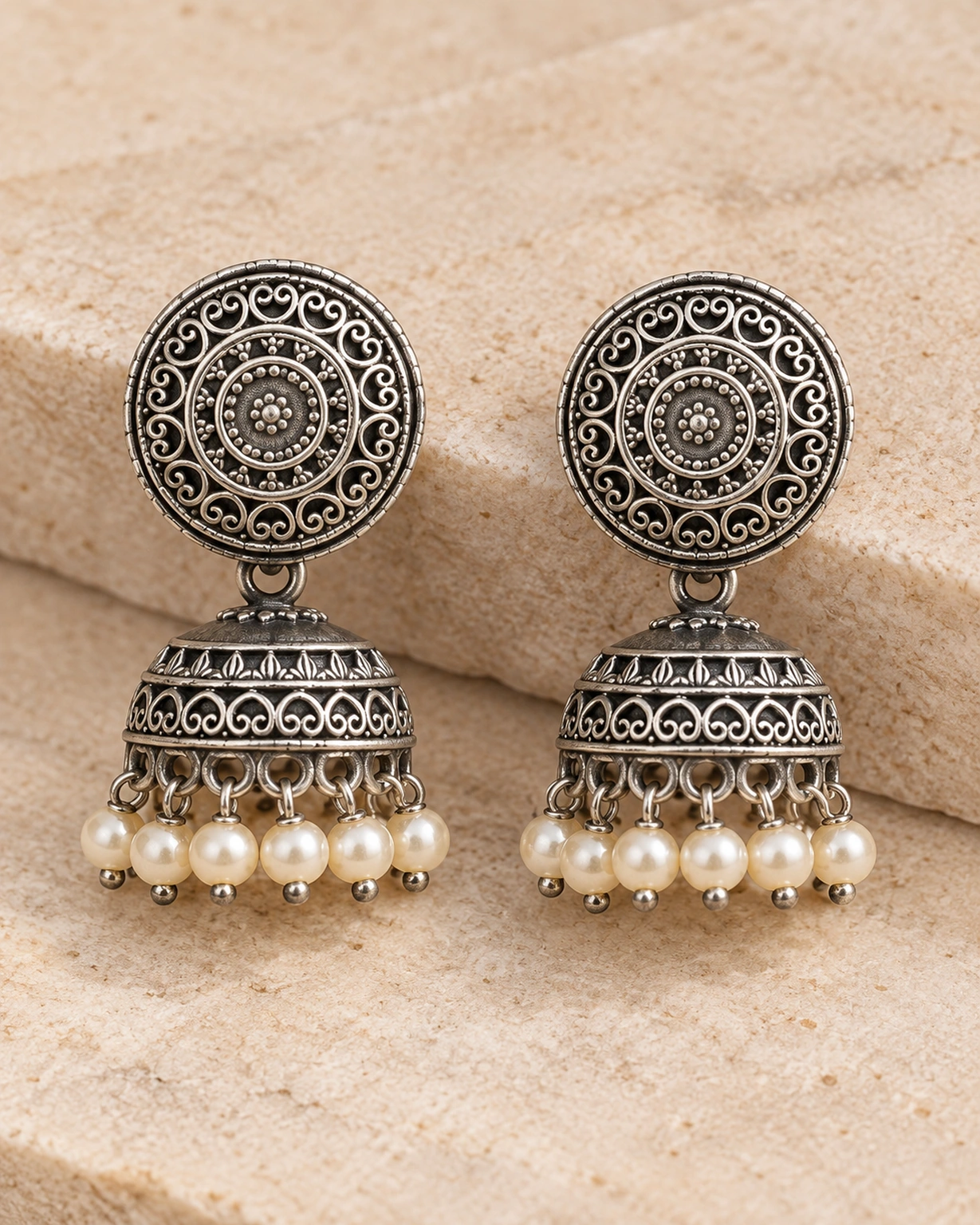 Close-up of round filigree jhumka earrings with cream pearl drops