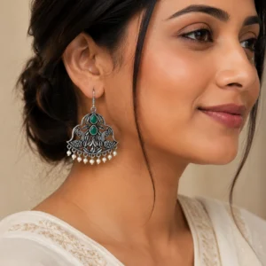 Green peacock hook earrings worn naturally with an ivory outfit.