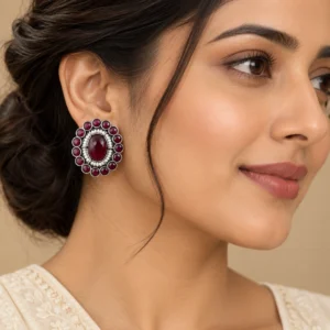 Maroon round stud earrings worn naturally with an ivory outfit.