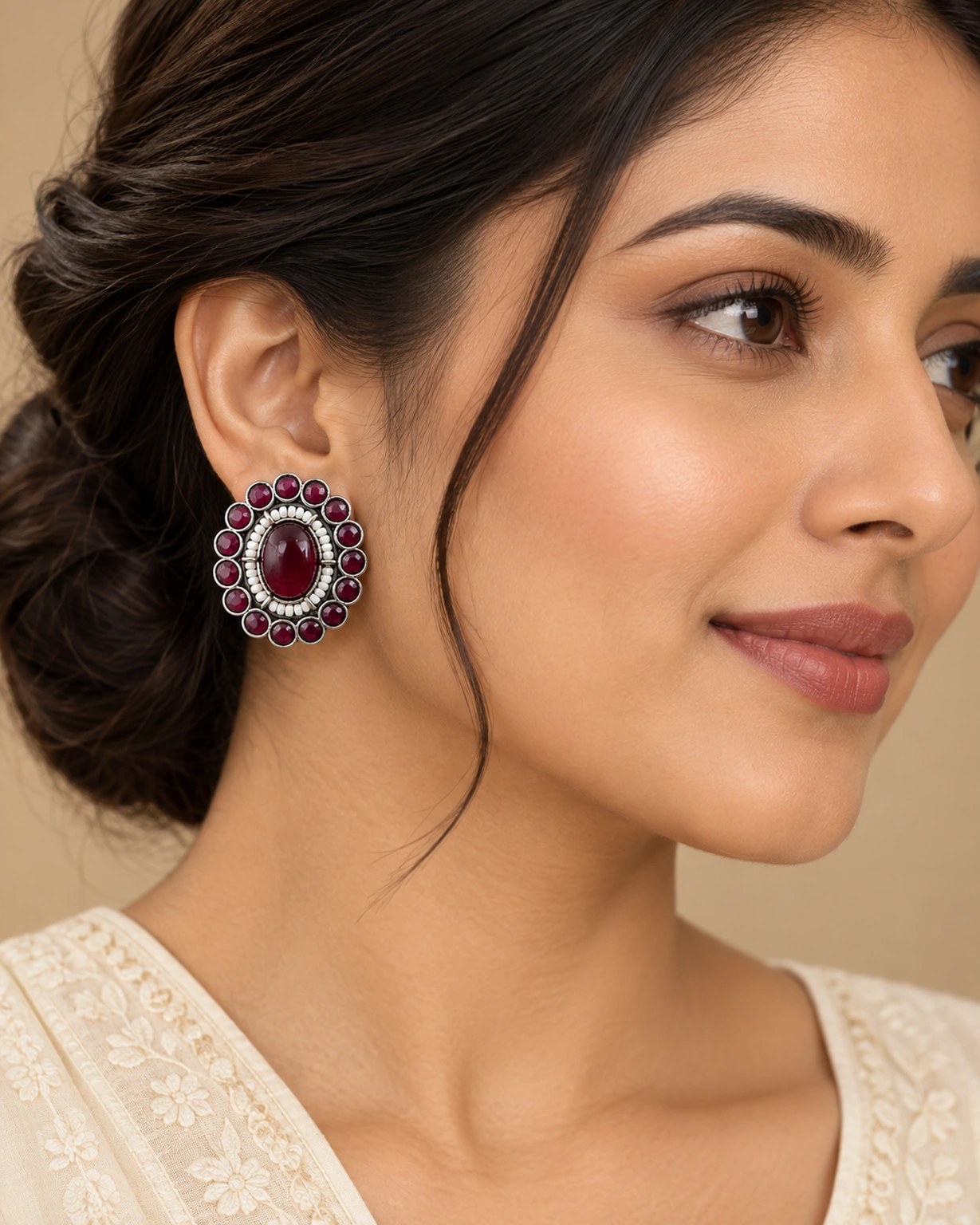 Maroon round stud earrings worn naturally with an ivory outfit.