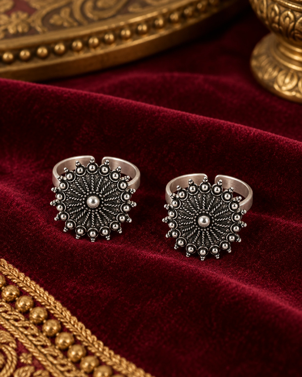 Matching floral oxidised toe rings displayed on royal burgundy velvet