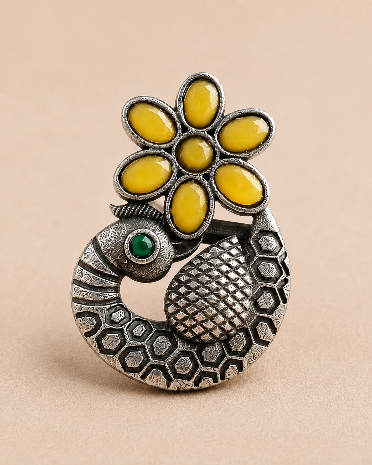 Close-up of six yellow petals, a green eye and textured silver-tone peacock detailing.